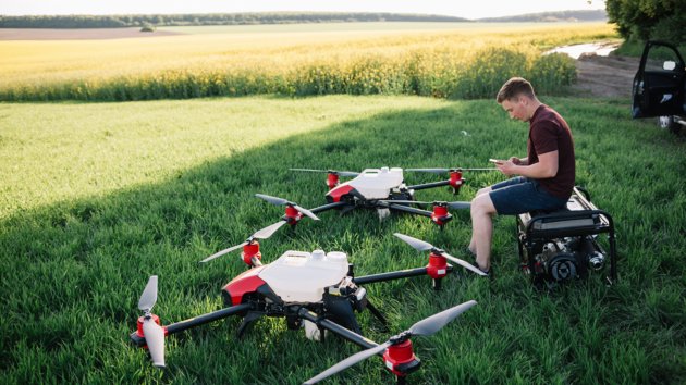 A person in the field with two UAVs