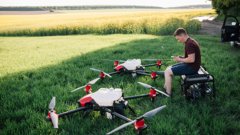 A person in the field with two UAVs