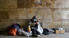 A homeless person sitting on the street surrounded by their belongings