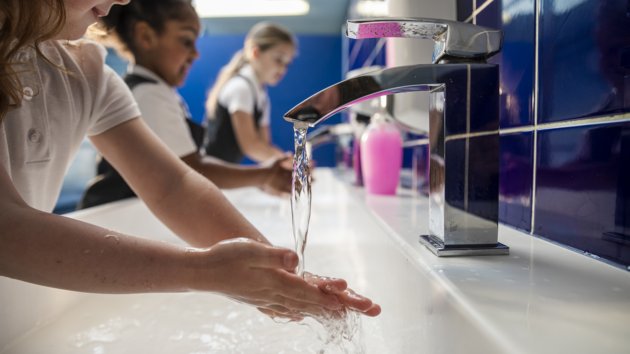 school children at a sink, washing their hands