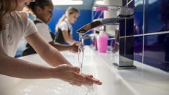 school children at a sink, washing their hands